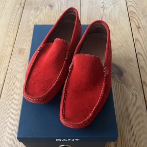 Röda mockaloafers från Gant - Snygga röda loafers i mocka från Gant. Perfekta för en stilren look med en bekväm passform. Skorna har en klassisk design med synliga sömmar och en robust sula.