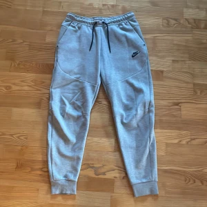 Nike Tech Byxor  - Gråa Nike Tech byxor i 10/10 skick ✅ Byxorna är i storlek M ✅ Dom köptes för 1199 kr och jag säljer dom för endast 399 kr ✅ Jag har en svart/grå fleece i nyskick om ni vill köpa med den ✅