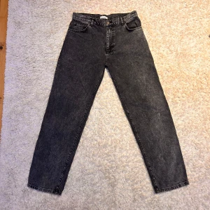 Gråsvarta jeans från Woodbird - Gråsvarta jeans ifrån Woodbird som är i bra skick och som är använda varsamt. Storleken är 31/32 och har en lös passform.  Man kan få dem för 249kr vid en snabb affär