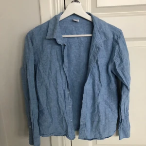 Blå linneskjorta från Lindex - Säljer en stilren blå linneskjorta från Lindex i storlek 158. Skjortan har långa ärmar och knappar framtill. Perfekt för en avslappnad och luftig stil. 🌿