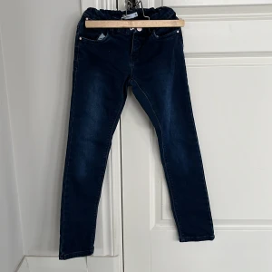 Mörkblå jeansleggings från Name It - Säljer ett par mörkblå fodrade jeansleggings från Name It i storlek 140. De har en elastisk midja för extra komfort och en klassisk jeanslook med bakfickor. Perfekta för en stilren och bekväm vardagsstil.