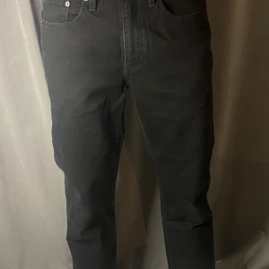 Svarta Levis 514 jeans - Snygga svarta Levis 514 jeans med klassisk femficksdesign och knappgylf.  Märkesetikett på baksidan och Levis Premium-märke på insidan.