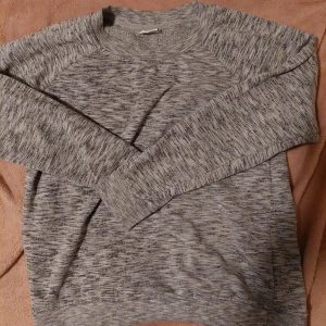 Gråmelerad tröja - Säljer en stilren gråmelerad tröja med rund halsringning och långa ärmar. Perfekt för en avslappnad look. Tröjan har en mjuk och bekväm passform.