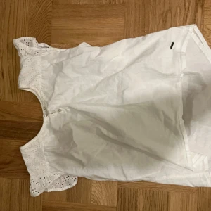 Vit blus från Pepe Jeans - Säljer en söt vit blus från Pepe Jeans med spetsdetaljer och knappar framtill. Blusen har korta ärmar och är perfekt för en somrig look. Passar bra till både jeans och kjol.