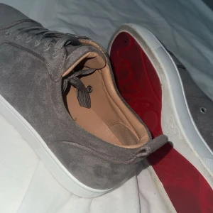Grå sneakers med röd sula från Christian Louboutin - Snygga grå sneakers från Christian Louboutin, självklart äkta. Priset är ej hugget i sten! 🪨 