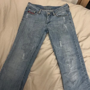 Blå lågmidjade jeans med broderi - Snygga blå jeans med unikt broderi på framsidan. Låg midja och raka i modellen! 