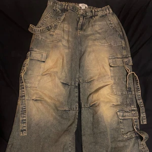 Blå cargopants med fickor och remmar - Säljer ett par coola blå cargopants med flera fickor och justerbara remmar. Från Urban outfitters