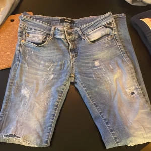 Replay jeans - Säljer ett par snygga blå jeans från Replay med slitna detaljer och klassisk femficksdesign. Perfekta för en avslappnad stil. Skriv vid frågor!