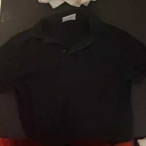 Mörkblå pikétröja från Bruun & Stengade - Säljer en stilren marinblå pikétröja från Bruun & Stengade. Perfekt för en avslappnad men ändå snygg look. Tröjan har en klassisk krage och knappar framtill.