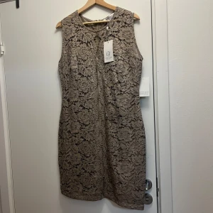 Beige spetsklänning från Chiara Forthi - Beige klänning i spets från Chiara Forthi. Den är ärmlös och har en figurnära passform med dragkedja i ryggen. Den är helt oanvänd. 