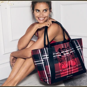 Tote bag från Victoria's Secret - Rutig shoppingväska / Tote Bag i rött och svart från Victoria's Secret. Väskan har svarta handtag och ett dekorativt blommönster på framsidan. Helt ny och oanvänd, i originalförpackning.