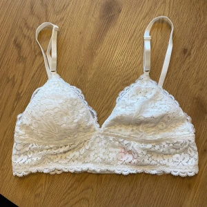Vit spetsbralette från Hunkemöller - Hunkemöller spetsbralette som är aldrig använd. Den har justerbara axelband och en mjuk spetsdesign med hakknäppning bak.  Storlek M men passar även S.