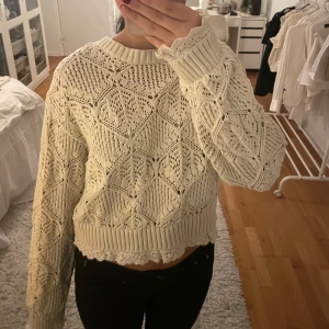 Beige stickad tröja med spetsdetaljer - Säljer en snygg beige stickad tröja med vackra spetsdetaljer. Tröjan har ett fint mönster och är lite croppad med långa ärmar. Perfekt för en mysig dag.