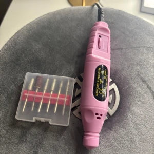 Rosa elektrisk nagelfil med tillbehör - Säljer en rosa elektrisk nagelfil med flera olika sliphuvuden i en praktisk förvaringslåda. Perfekt för manikyr och pedikyr hemma. Enkel att använda med justerbar hastighet.