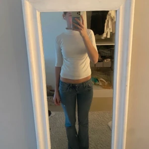 Vit polotröja med trekvartsärm - Säljer en stilren vit polotröja med trekvartsärm. Perfekt för en minimalistisk look och passar bra till jeans eller kjol. Tröjan har en tight passform som framhäver figuren.