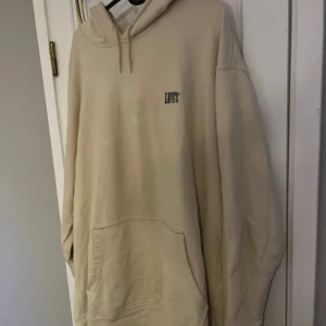 Beige hoodie från Levi's - Säljer en stilren beige hoodie från Levi's i storlek XL. Den har en klassisk design med en känguruficka och justerbar huva. Perfekt för en avslappnad look.