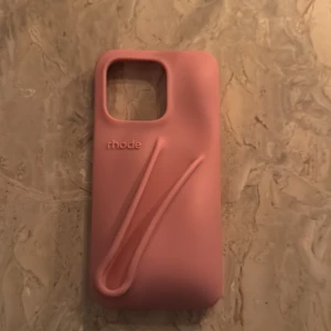 Rosa mobilskal från Rhode - Snyggt rosa mobilskal från Rhode med en stilren design och praktiskt grepp. Skalet har en mjuk yta och är perfekt för att skydda din telefon samtidigt som det ger ett trendigt utseende. Jag hann använda det i ca 2 veckor innan jag fick en ny mobil i julklapp, då skalet är i princip oanvänd! 