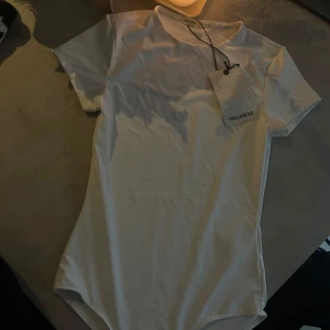 Vit bodysuit från Pull&Bear - Säljer en vit bodysuit från Pull&Bear. Den har korta ärmar och en rund halsringning. Endast testad en gång, lite smink finns på insidan vid halsen men går att tvätta.