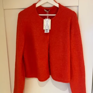 Röd kofta från Gina Tricot - Säljer en snygg röd kofta från Gina Tricot i storlek XL. Koftan har långa ärmar och knappar framtill. Perfekt för att lägga till en färgklick i din garderob! 