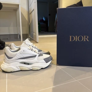 Dior b22 - Snygga vita sneakers från Dior med grå detaljer och snörning. Skorna har en chunky sula och perforerade sidopaneler för extra stil. Perfekta för en trendig look. Skorna är äkta, de finns kvitto, box och allt og tillkommer.
