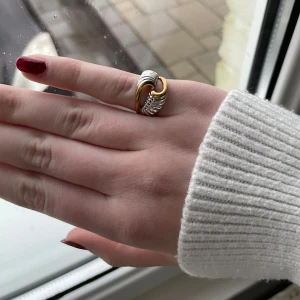 Tvåfärgad ring i guld och silver - Elegant ring med en unik design i både guld och silver. Den har en flätad look som ger en modern och stilren känsla. Perfekt för att ge en extra touch till din outfit. Obs kan finnas spår av rost. Dock schysterbar ring, kan alltså passa alla. Skriv vid frågor!!!🫶🏻💗