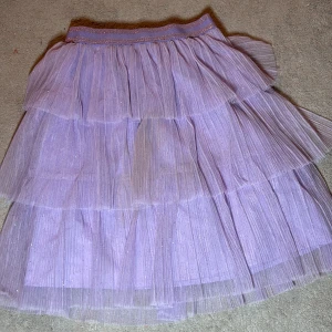 Lila tyllkjol från H&M - Säljer en lila tyllkjol från H&M med flera lager och glittrande detaljer. Kjolen har en elastisk midja för bekväm passform och är perfekt för att lägga till en touch av glamour till din outfit. 🌟