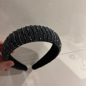 Blått diadem med pärlor - Snyggt svart diadem dekorerat med glittrande pärlor. Perfekt för att ge en extra touch till din outfit. Diademet har en bred design som ger en elegant look.