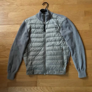 Cardigan Woolrich - Tjenare! Säljer nu min stilrena grå cardigan från Woolrich med quiltad framsida och dragkedja. Jackan har långa ärmar och en hög krage som är perfekt för kyligare dagar. Materialet är en blandning av ull och polyester vilket ger både värme och komfort. Cardiganen är i skicket 8,5/10 då det var ett litet hål i höger axel, som nu är igensydd av en skräddare så märket syns ej längre. Den är i storlek M och passar dig som är 170-180. Vid fler frågor kontakta via dm :) 