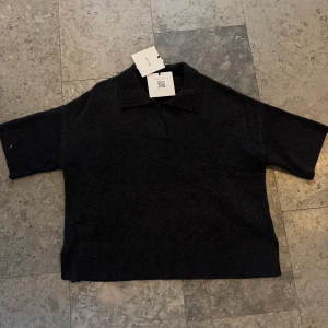 Mörkgrå kashmirtröja från Soft Goat - Säljer en stilren mörkgrå tröja från Soft Goat. Tröjan har en klassisk krage och trekvartsärmar, perfekt för en avslappnad look. Kashmir är mjukt och bekvämt, vilket gör den idealisk för kyligare dagar.