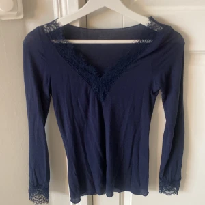 Mörkblå långärmad topp från Intimissimi - Säljer en  mörkblå långärmad topp från Intimissimi med fin spetsdetalj vid halsringning och ärmslut. 