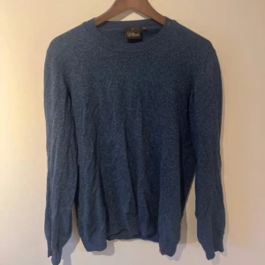 Blå tröja från Oscar Jacobson - Snygg blå tröja från Oscar Jacobson, tillverkad i Italien. Tröjan har en klassisk design med rund hals och långa ärmar. Perfekt för en stilren look.