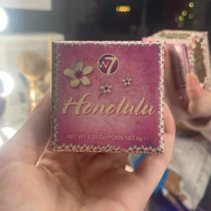 Honolulu Bronzing Powder från W7 - Säljer en Honolulu Bronzing Powder från W7. Den kommer i en söt rosa förpackning med blommönster och innehåller en liten borste. Perfekt för att ge ansiktet en solkysst look.