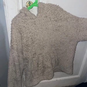 Beige fluffig hoodie från H&M - Mysig beige hoodie från H&M i fluffigt material. Perfekt för kyliga dagar med sin varma och bekväma design. Tröjan har en luva och långa ärmar, vilket gör den idealisk för avslappnade tillfällen.
