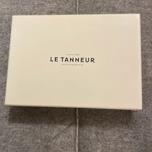 Brun plånbok från Le Tanneur - Elegant brun plånbok i skinn från Le Tanneur. Den har flera fack för kort och en dragkedja för mynt. Perfekt för att hålla ordning på dina värdesaker med stil.