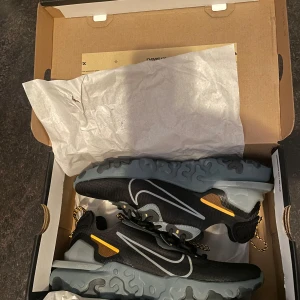 Nike D/MS/X sneakers i svart och grå - Snygga Nike D/MS/X sneakers i svart med grå och gula detaljer. Skorna har en unik sula med vågigt mönster och snörning för en perfekt passform. Perfekta för en sportig look.