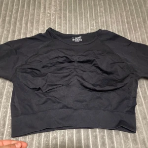Idrottströja  - Säljer en svart långärmad topp med tumhål. Perfekt för träning eller en avslappnad dag. Toppen har en tight passform och är tillverkad i ett mjukt och stretchigt material.