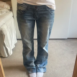 Ljusblå bootcut jeans med unika fickor - Snygga blå bootcut jeans med en klassisk femficksdesign.  Jeansen har låg midja och stängs med dragkedja och knapp. de har slitningar i hälarna, då de varit för långa för mig. Skriv för frågor!💕