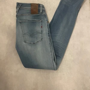 Replay anbass - Snygga blå jeans från Replay, modell Anbass. De har en klassisk femficksdesign med knappgylf och dragkedja. Perfekta för en avslappnad stil. Hör av er vid frågor!