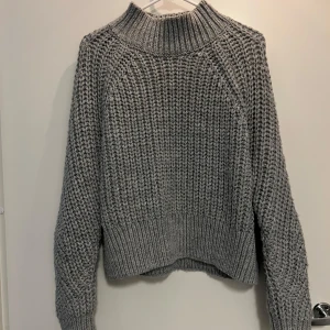 Stickad tröja - Säljer en mysig grå/blå stickad tröja från H&M. Tjockt stickad och varm, perfekt för kyliga dagar. 