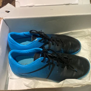 Svart och blåa inneskor - Snygga fotbollsskor i svart och blått med snörning. Perfekta för spel på planen med en stilren design och bra grepp på sulan.