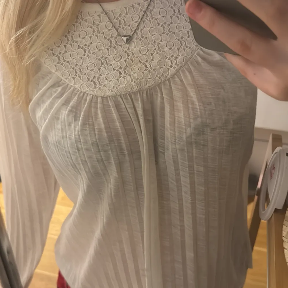 Säljer en söt vit långärmad topp med spetsdetaljer runt halsen. Toppen har en ribbad struktur och är perfekt för en avslappnad stil. Passar bra till både jeans och kjol. 🌼Passar som storlek xs. Neuletakit & Villapaidat.