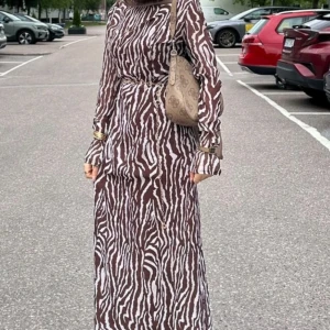 Brun och vit zebramönstrad klänning - Jättefin maxiklänning i chiffon med långa utsvängda ärmar! Den har dold kedja i midjan. Inte stretchig. Ca 147cm från hals och nedåt. Nästan nyskick, endast använd 2 ggr. Den är genomskinlig. Skulle säga att den passar XS/S.