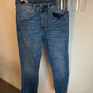 Blå jeans med hög midja - Snygga blå jeans med hög midja och klassisk femficksdesign. De har en knappgylf och en läderpatch baktill. Perfekta för en avslappnad stil.