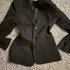 Svart kavaj med öppen rygg - Snygg svart kavaj med unik design och öppen ryggdetalj. 