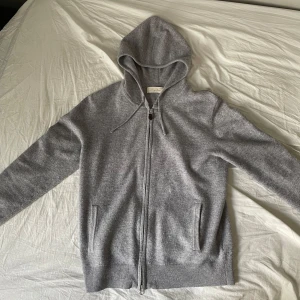Grå hoodie från Sagless - Säljer en stilren grå hoodie från Sagless i kashmirblandning. Den har dragkedja framtill och en praktisk huva. Perfekt för kyliga dagar!