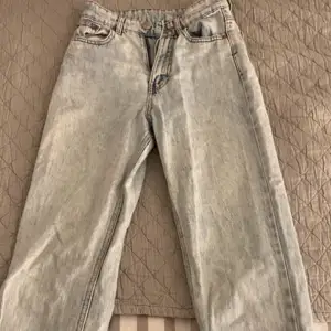 Säljer ett par ljusblå jeans med klassisk femficksdesign. De har en rak passform och är perfekta för en avslappnad stil. Jeansen har en dragkedja och knapp framtill.