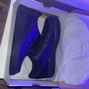 Svarta Nike Air Force sneakers - Helt nya snygga svarta Nike Air Force sneakers. Aldrig använda bara testat de nån gång inomhus. Anledningen till försäljningen är att de inte passar min stil.  Köpta för 1400 med box! säljs för  950 kr.  Med fri frakt 