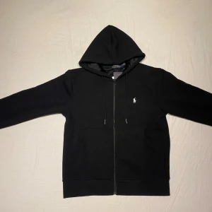 Polo Ralph lauren zip-up hoodie - Polo Ralph lauren zip-up hoodie i ny skick. Säljer då den inte passade mig. Materialet på insidan är väldigt mjukt och tjockt.