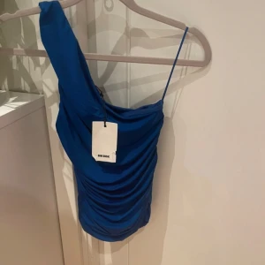Blå oneshoulder topp bikbok - Supersnygg helt ny och oanvänd topp från bikbok med prislapp kvar. Tröjan är oneshoulder med en fin draperad design. Säljer då den ännu inte kommit till användning💕