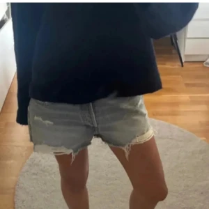 Grå jeansshorts med slitningar - Snygga grå jeansshorts från Zara med slitna detaljer och fransig kant. Perfekta för en avslappnad stil. De har en klassisk femficksdesign och knappgylf.